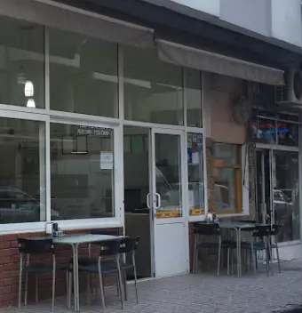 Restoranın camlı cephesi, giriş kapısı ve kaldırımdaki masalar